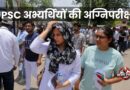 भीषण गर्मी में UPSC परीक्षा केंद्र के बाहर खड़े अभ्यर्थी, पानी की बोतल और सिर ढककर धूप से बचते हुए।